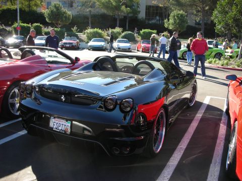 1992 Ford Crown Victoria - A black Ferrari F430 Spider is parked at an outdoor car meet, with several other vehicles visible.