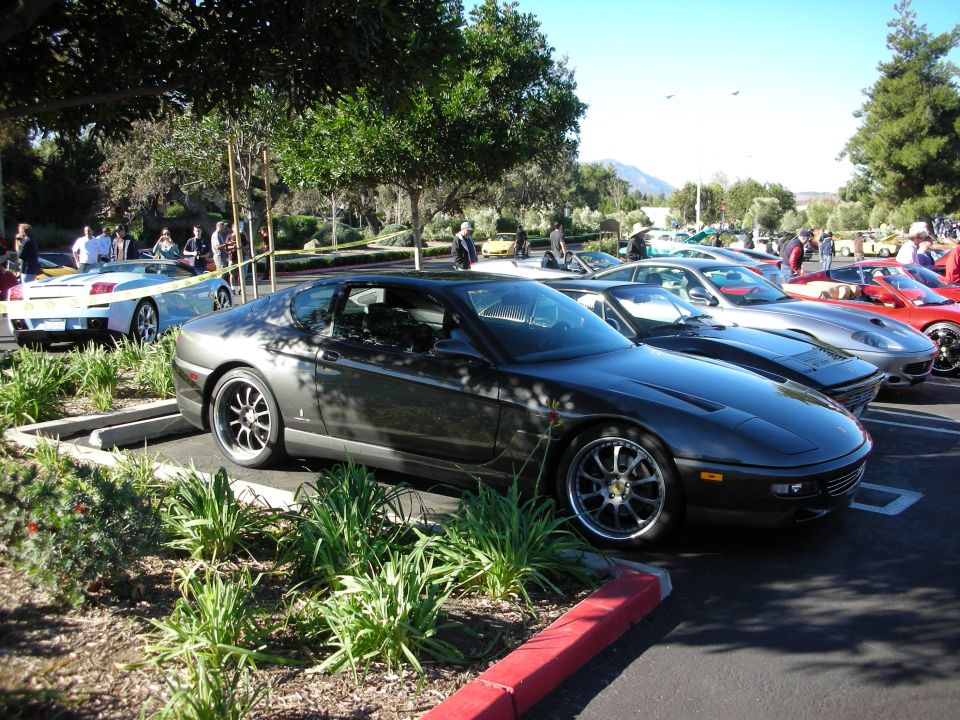 Dark gray coupe with multi-spoke wheels parked in a lot with other cars