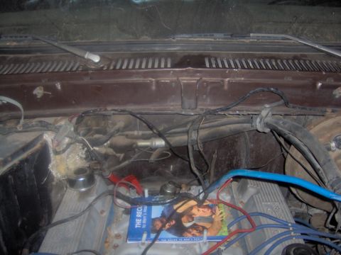 1978 Ford Bronco - A cluttered engine bay view shows various components and a magazine placed on the engine.