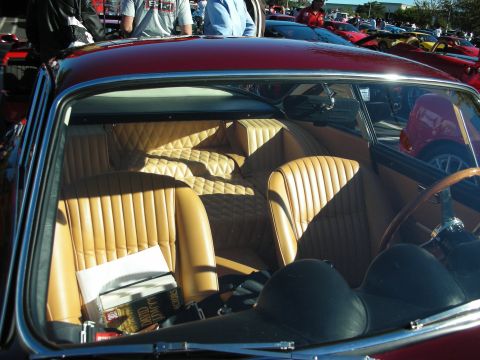 1992 Ford Crown Victoria - The interior of a classic red car with tan seats and a book on the passenger seat is visible, with other cars in the background.