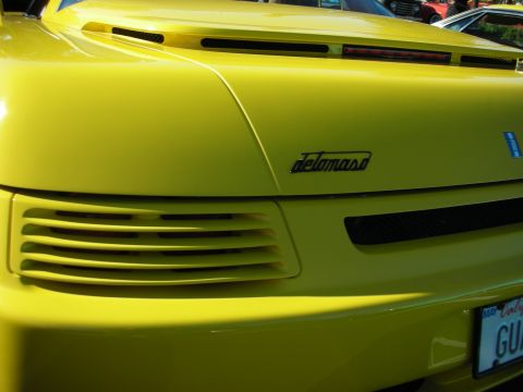 1992 Ford Crown Victoria - Rear view of a yellow sports car with a distinctive 'de Tomaso' emblem and horizontal vents.