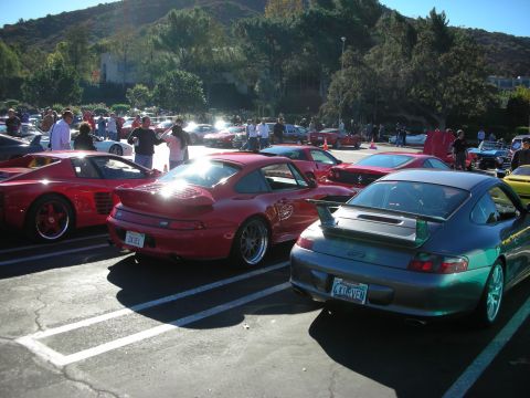 1992 Ford Crown Victoria - A gathering of sports cars, a red Ferrari and a gray Porsche GT3, parked in an outdoor lot.