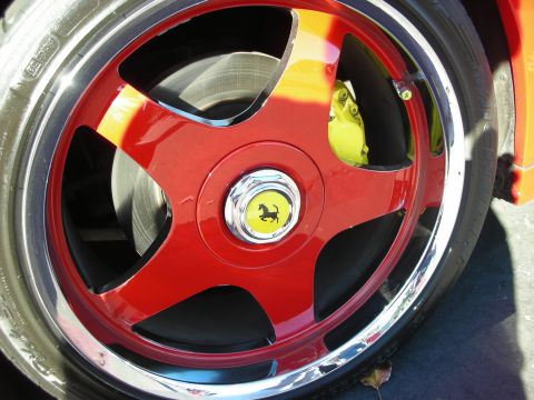 1992 Ford Crown Victoria - Close-up of a red Ferrari wheel the iconic Prancing Horse emblem and a bright yellow brake caliper.