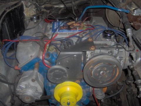 1978 Ford Bronco - Engine bay view of a V8 motor, showing various components and wiring. A magazine rests on the engine.