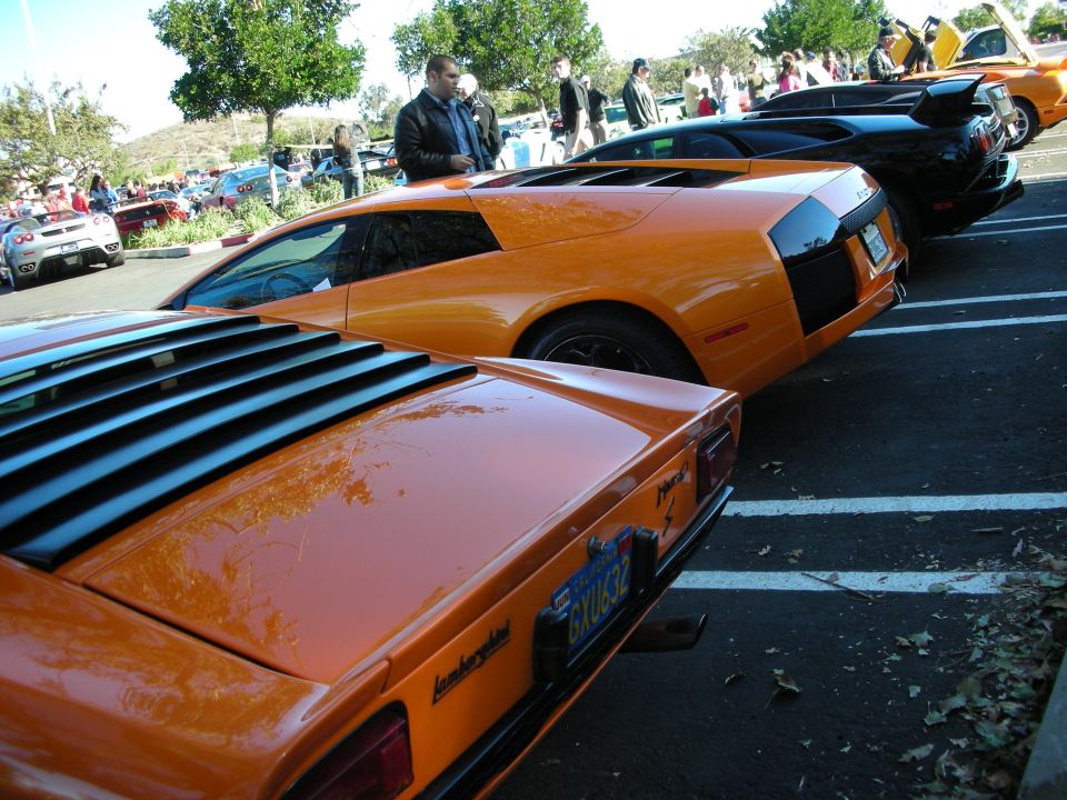 Rear view of an orange Lamborghini with louvers on the engine cover and a license plate
