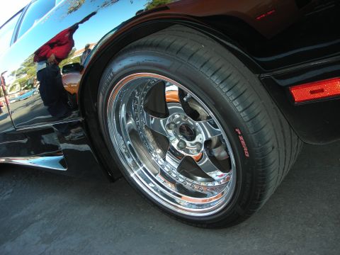 1992 Ford Crown Victoria - Chrome wheel and Pirelli P Zero tire detail on a black vehicle. Orange reflector is visible.