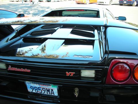 1992 Ford Crown Victoria - The rear of a black Lamborghini Diablo VT is shown, with a spoiler and distinctive taillights.