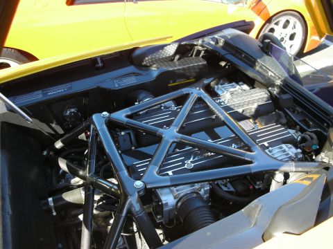 1992 Ford Crown Victoria - The engine bay of a car is shown, with a yellow car in the background.