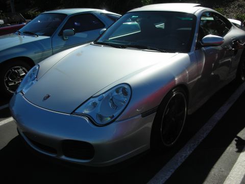 1992 Ford Crown Victoria - A silver Porsche 911 is parked in a lot, with another vehicle visible to its left.