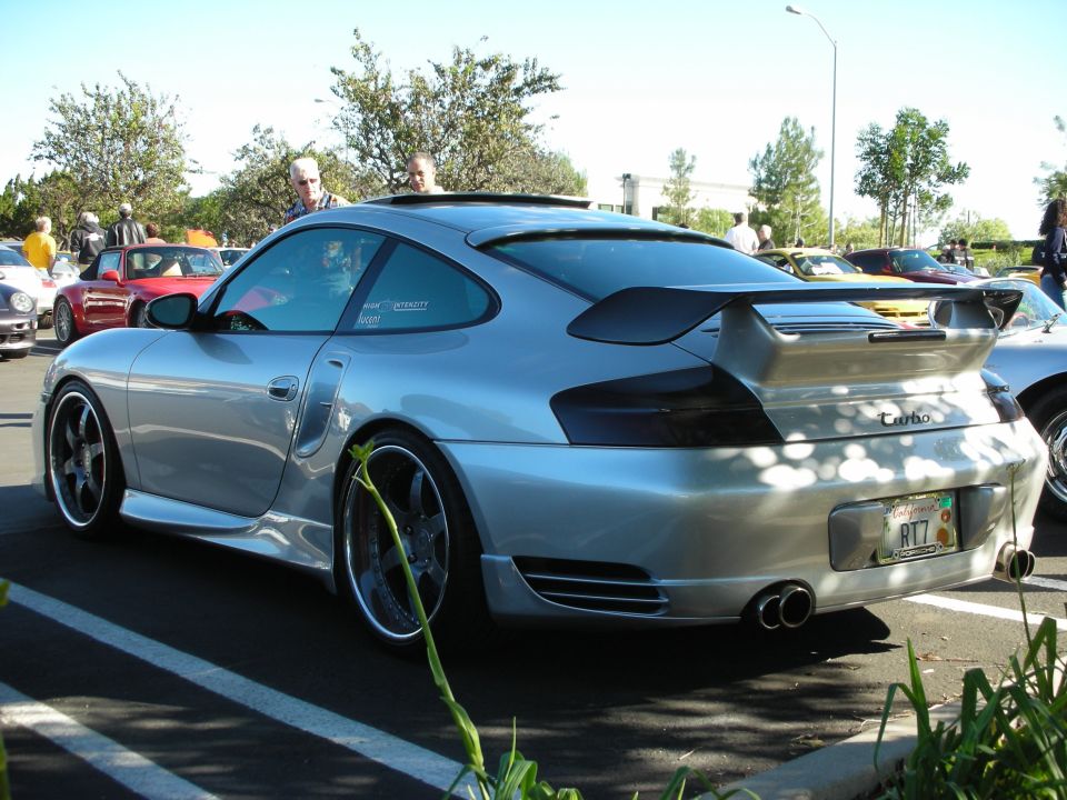 Silver Porsche 911 Turbo with a large rear spoiler and dual exhaust pipes