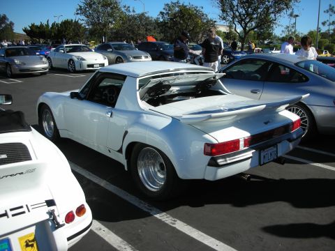 1992 Ford Crown Victoria - A white sports car is parked in a lot with other vehicles.