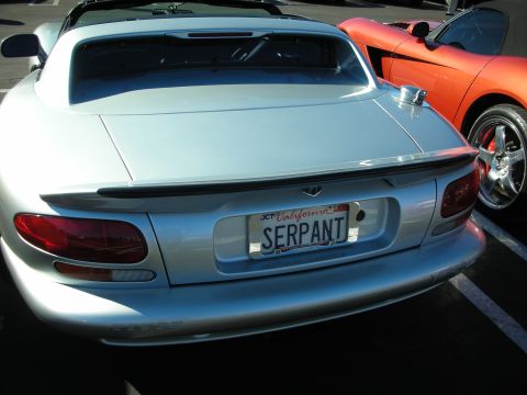 1992 Ford Crown Victoria - Rear view of a silver Dodge Viper sports car with a custom license plate, parked next to an orange car.