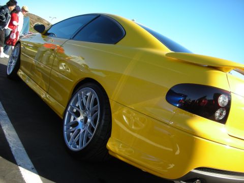 1992 Ford Crown Victoria - Yellow coupe with custom wheels and tinted taillights parked outdoors.