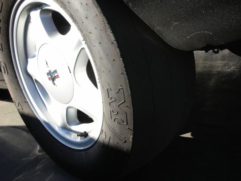 1992 Ford Crown Victoria - A close-up view of a racing tire and wheel, a tri-color emblem on the hubcap.