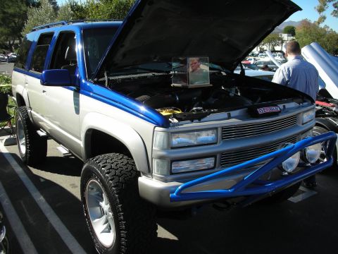 1992 Ford Crown Victoria - A modified Chevrolet Tahoe is displayed with its hood open, revealing the engine bay and a framed photo.