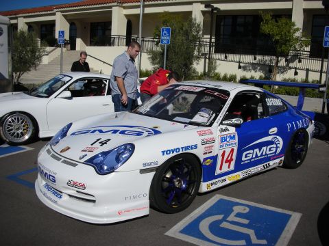 1992 Ford Crown Victoria - A white and blue Porsche race car with racing decals is parked in a handicapped spot, with another white Porsche in the background.