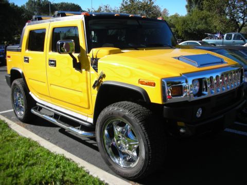 1992 Ford Crown Victoria - This yellow Hummer H2 features flame graphics and large chrome wheels, parked outdoors.