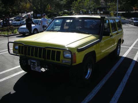 1992 Ford Crown Victoria - A yellow Jeep Cherokee XJ is parked in a lot, equipped with a snorkel and brush guard.