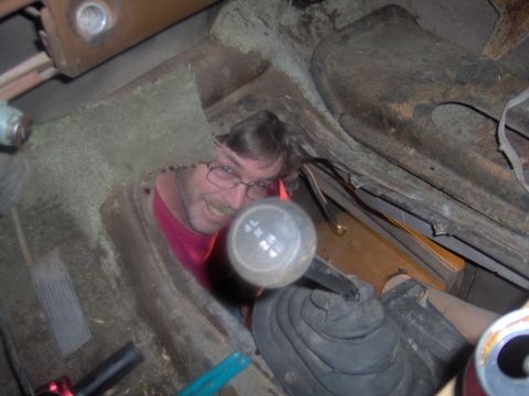 1978 Ford Bronco - Man looking through floor opening at the gear shifter in a 1978 Ford Bronco.