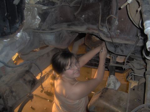 1978 Ford Bronco - A person works on the underside of a vehicle, likely during an installation or repair.