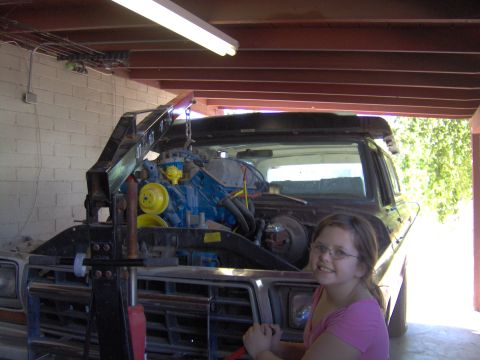 1978 Ford Bronco - A young girl poses in front of a Ford Bronco as its engine is being worked on.