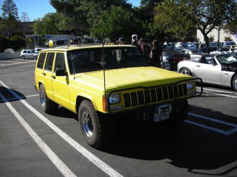1992 Ford Crown Victoria - Yellow Jeep Cherokee parked in a lot, with other vehicles visible in the background.