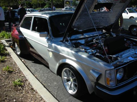 1992 Ford Crown Victoria - A custom Volvo 240 coupe with a widebody kit and open hood is parked outdoors.