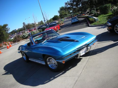 1992 Ford Crown Victoria - A blue convertible sports car is captured in motion on a bright, clear day, with other vehicles visible in the background.