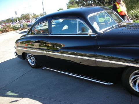 1992 Ford Crown Victoria - A black coupe with chrome accents and side pipes is parked on a paved surface.