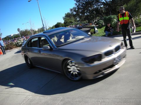 1992 Ford Crown Victoria - A brown BMW 7 Series sedan is captured in motion, its distinctive grille and custom wheels.