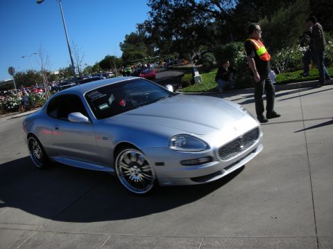 1992 Ford Crown Victoria - Silver Maserati coupe driving on pavement with people and other vehicles in the background.