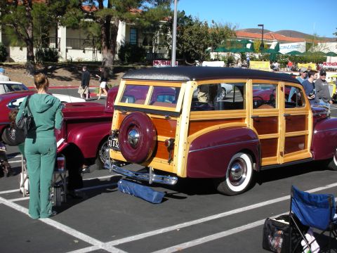 1992 Ford Crown Victoria - A classic woodie station wagon is parked at an outdoor event, with a red pickup truck beside it.