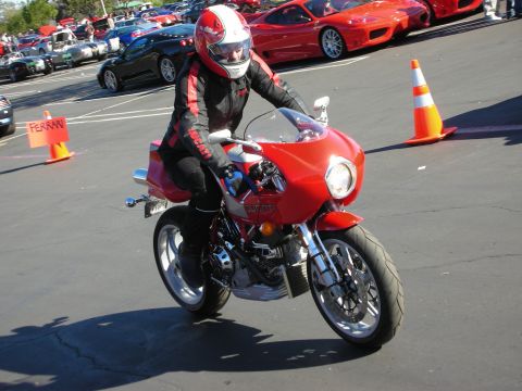 1992 Ford Crown Victoria - A rider in full gear on a red Ducati motorcycle is seen with several red Ferraris parked in the background.