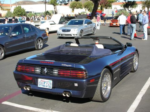 1992 Ford Crown Victoria - A dark blue convertible sports car is parked in a lot with other vehicles visible.
