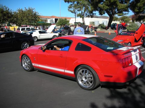 1992 Ford Crown Victoria - Red Ford Mustang coupe with white racing stripes parked at an outdoor event with other vehicles.
