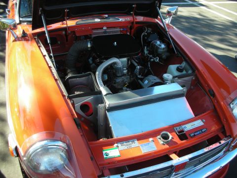 1992 Ford Crown Victoria - The engine bay of an orange MG sports car, a V8 engine and custom air intake system.