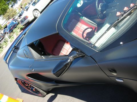 1992 Ford Crown Victoria - A matte black sports car with a red interior is parked in a lot.