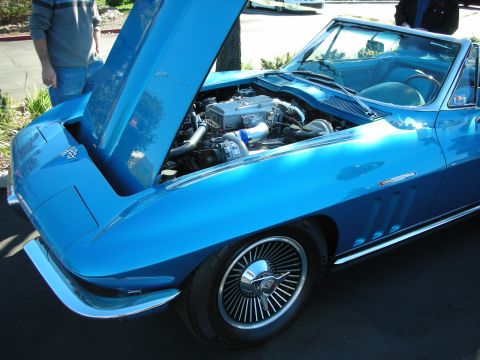 1992 Ford Crown Victoria - A blue 1965 Chevrolet Corvette convertible displays its engine with the hood raised, revealing chrome accents and a custom intake.