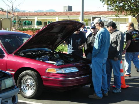 1992 Ford Crown Victoria - Several people gather around a red 1992 Ford Crown Victoria, examining its engine bay.
