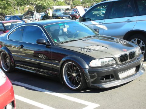 1992 Ford Crown Victoria - A modified black coupe with a carbon fiber hood and aggressive body kit is parked next to other vehicles.