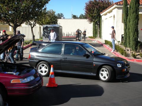 1992 Ford Crown Victoria - Side view of a dark gray hatchback with a spoiler, parked outdoors with other vehicles and people.