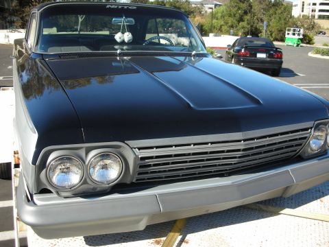 1992 Ford Crown Victoria - A classic car with a prominent grille and dual headlights is parked outdoors, with other vehicles visible in the background.