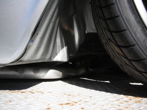 1992 Ford Crown Victoria - Close-up view of the undercarriage of a silver vehicle, showing the tire and exhaust system.