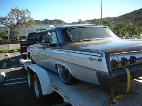 1992 Ford Crown Victoria - Custom 1961 Chevrolet Impala being transported on a trailer, with a black pickup truck in the background.