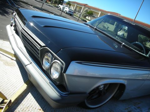 1992 Ford Crown Victoria - A classic car with a distinctive grille and dual headlights is loaded onto a trailer, with other vehicles visible in the distance.