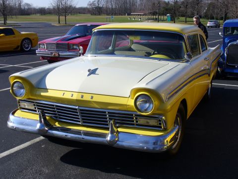 1991 Ford Probe - A classic yellow and white Ford sedan is parked in a lot with other vehicles.