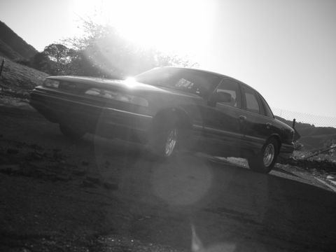 1992 Ford Crown Victoria - Black 1992 Ford Crown Victoria sedan angled on a dirt embankment under bright sun.