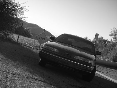 1992 Ford Crown Victoria - A 1992 Ford Crown Victoria is parked near a road with an 'END' sign, under a bright sky.