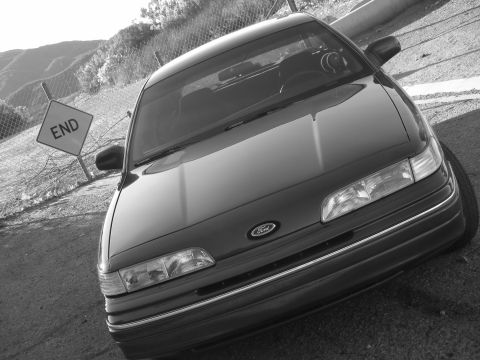 1992 Ford Crown Victoria - A 1992 Ford Crown Victoria is seen from the front, parked near a fence and an 'END' sign.