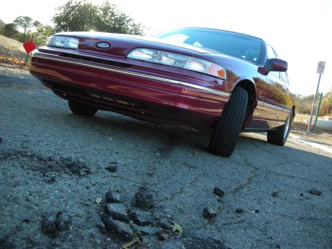 1992 Ford Crown Victoria - 1992 Ford Crown Victoria seen from a low angle on a street with potholes.